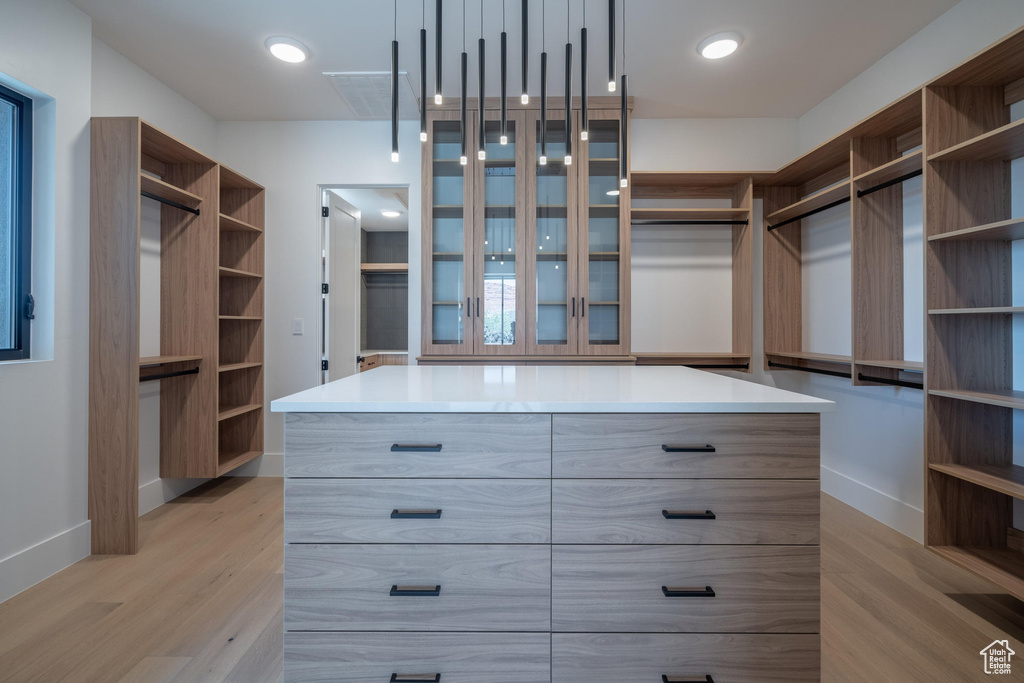 Walk in closet with light hardwood / wood-style flooring