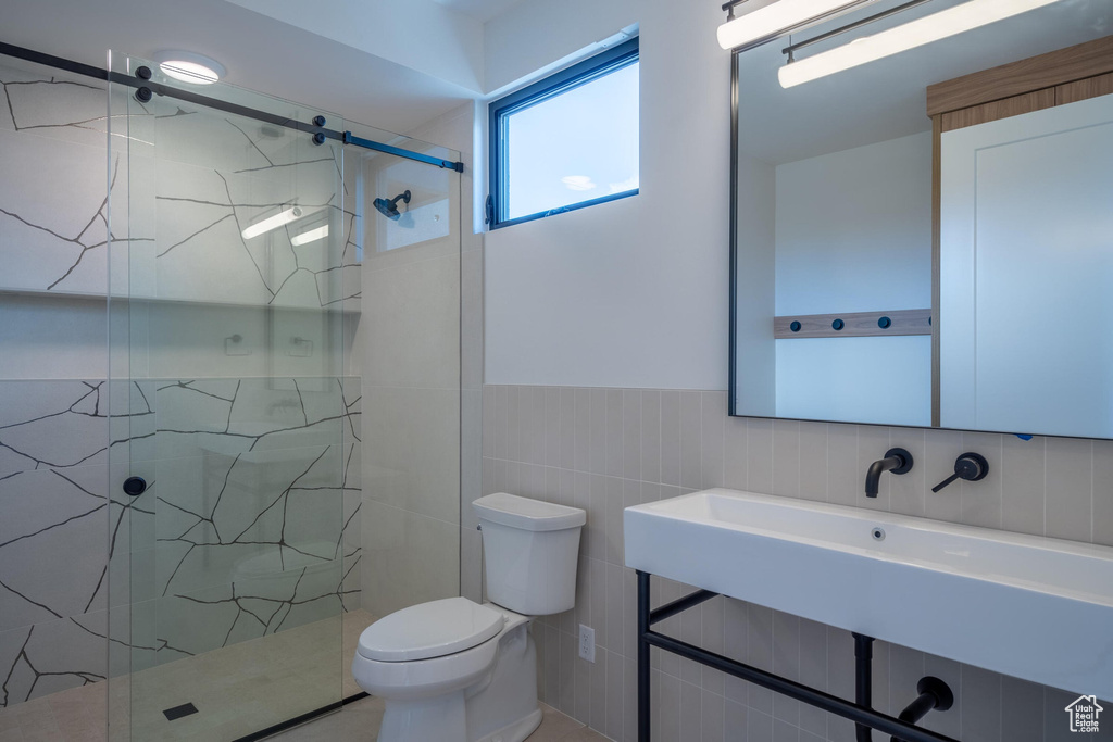 Bathroom featuring toilet, tile walls, and walk in shower