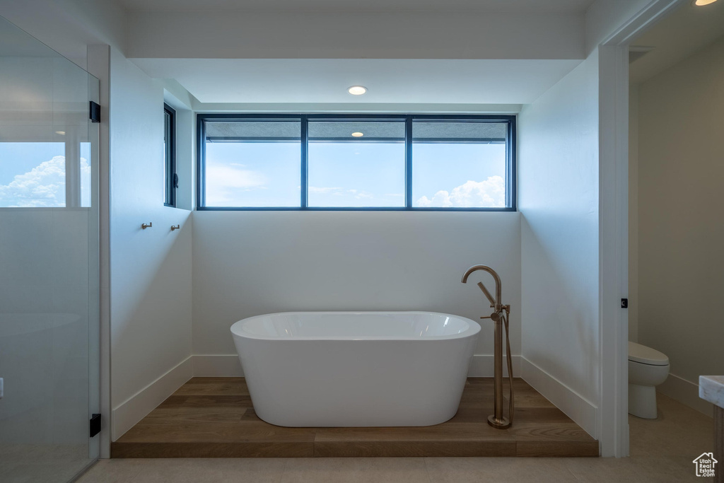 Bathroom with hardwood / wood-style floors, toilet, and a tub