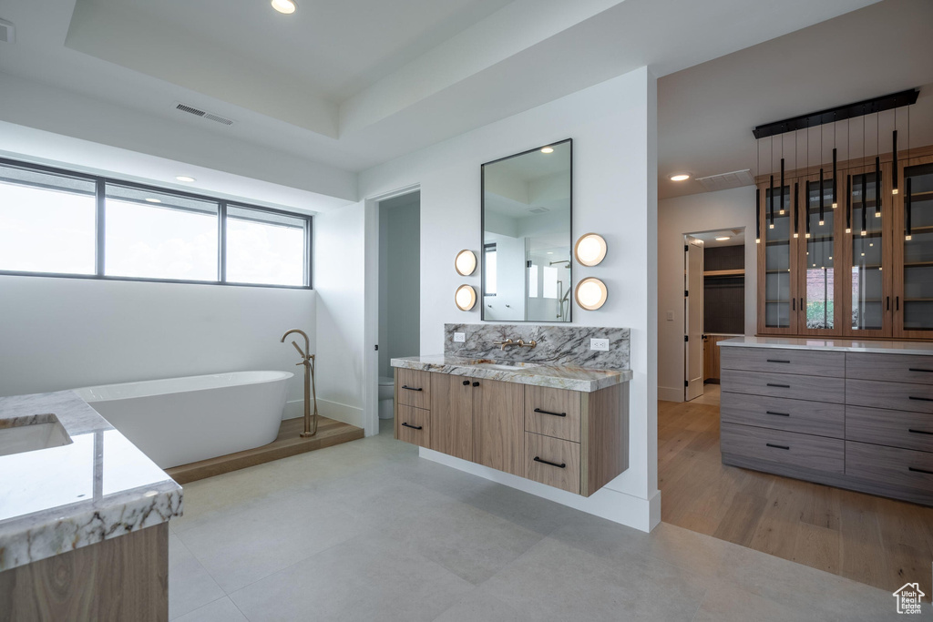 Bathroom with a bathing tub, vanity, and a raised ceiling