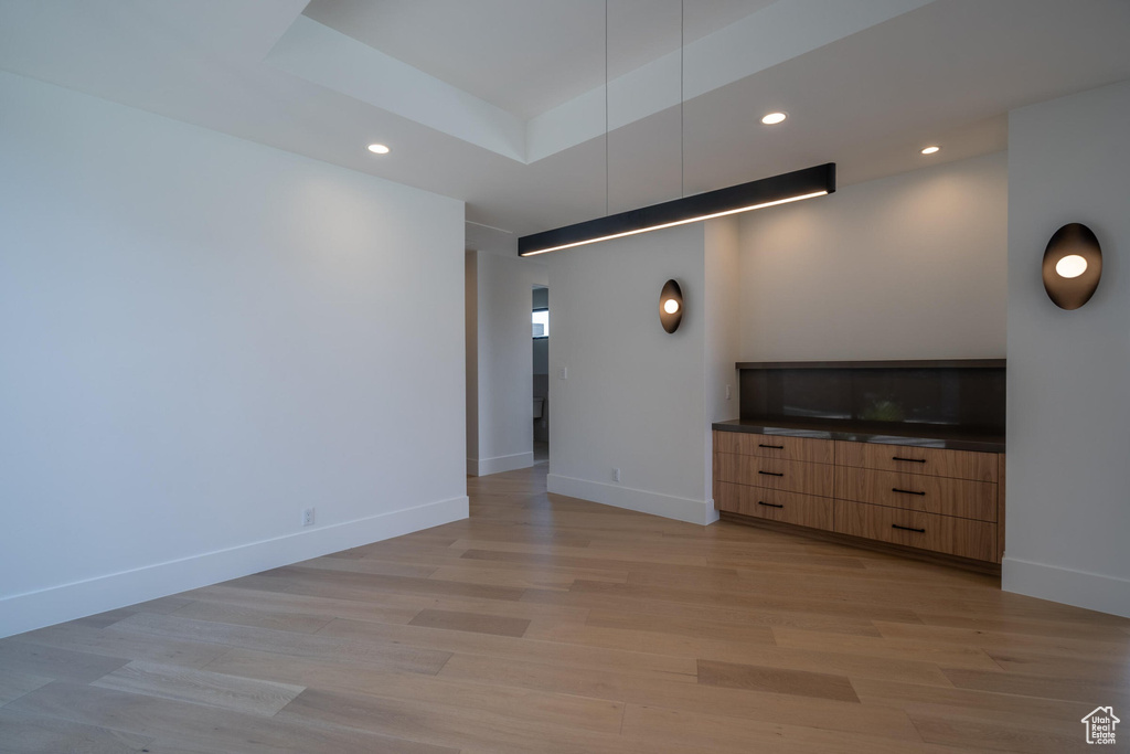 Unfurnished living room featuring a tray ceiling and light hardwood / wood-style flooring