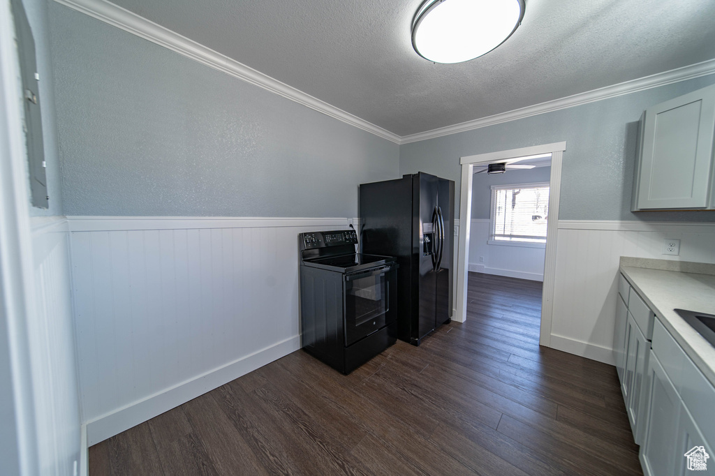 Kitchen featuring dark hardwood / wood-style flooring, a textured ceiling, crown molding, black appliances, and white cabinets