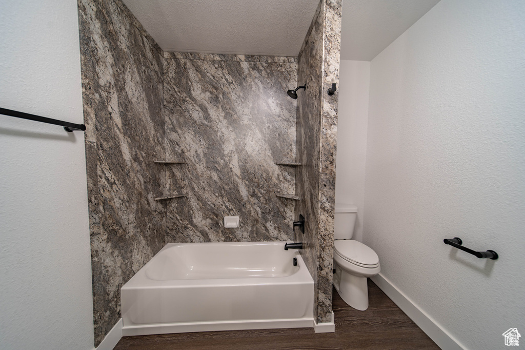 Bathroom featuring hardwood / wood-style flooring, toilet, shower / bath combination, and a textured ceiling
