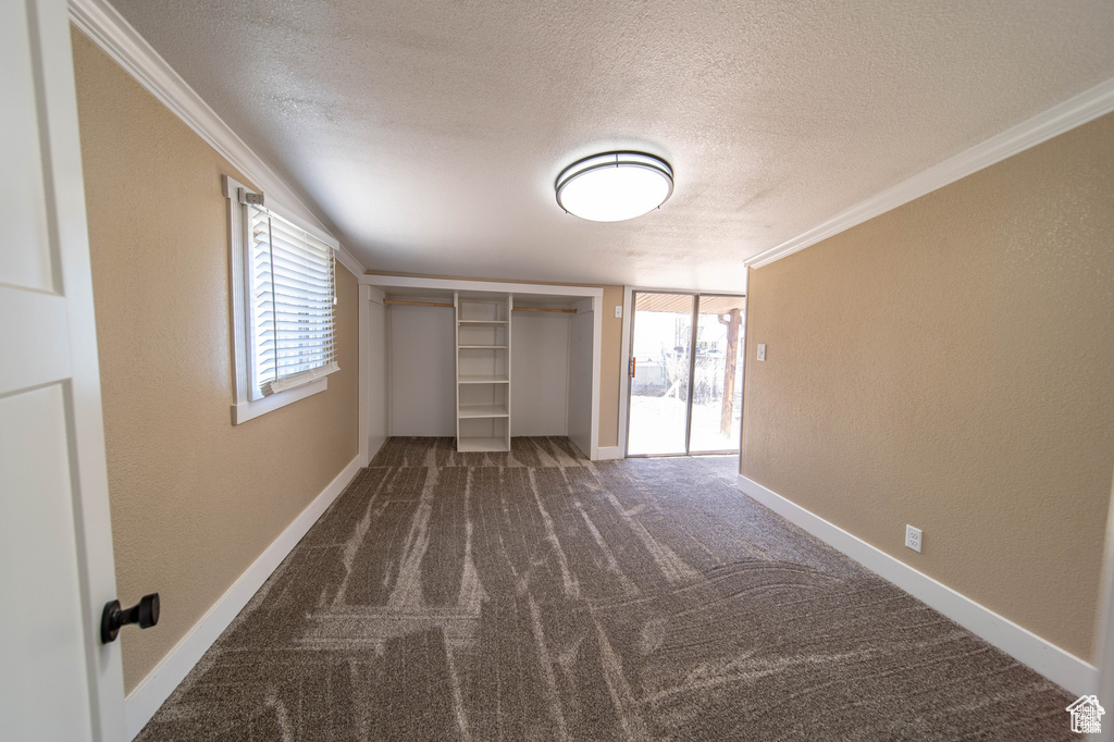 Unfurnished bedroom with a closet, dark colored carpet, a textured ceiling, and ornamental molding