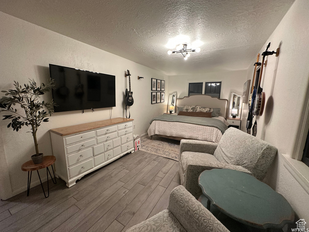 Bedroom featuring a textured ceiling, dark wood-type flooring, and an inviting chandelier