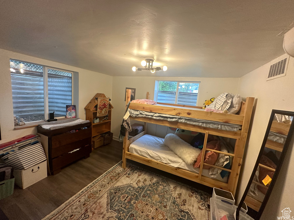 Bedroom with a notable chandelier and dark wood-type flooring