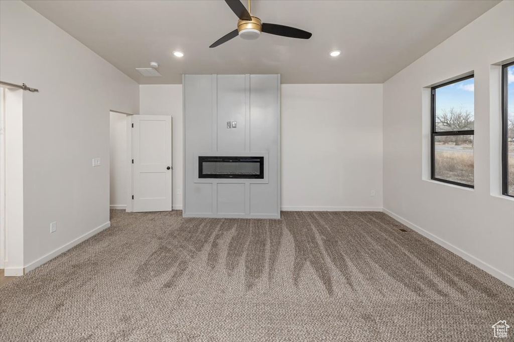 Unfurnished living room with carpet flooring and ceiling fan