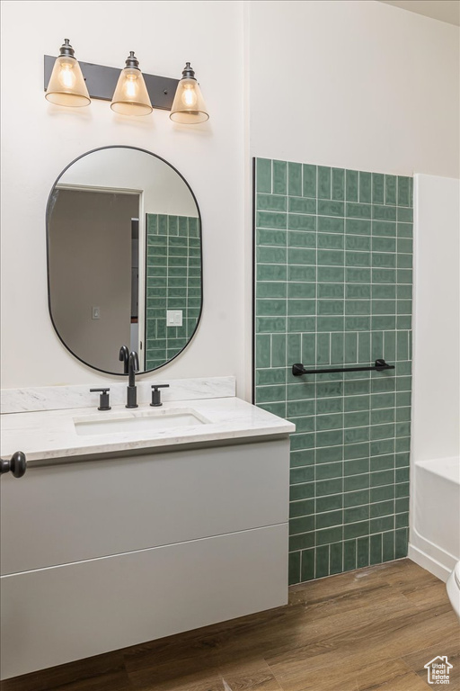 Bathroom featuring a bathing tub, vanity, wood-type flooring, and toilet