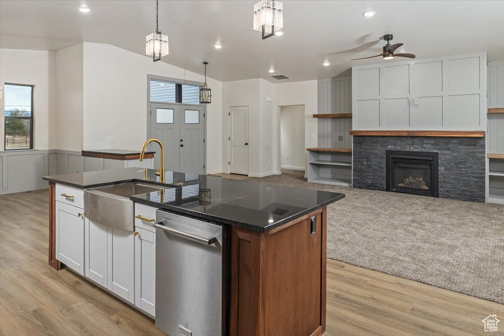 Kitchen with white cabinetry, a center island with sink, ceiling fan, and decorative light fixtures