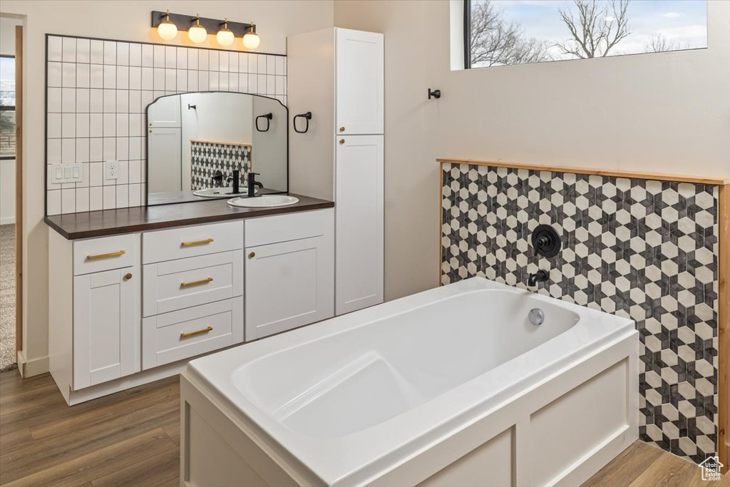 Bathroom featuring hardwood / wood-style flooring, vanity, and a tub to relax in