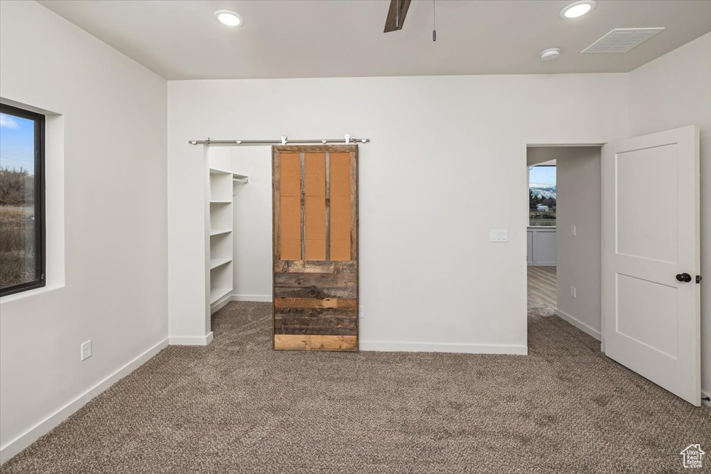 Unfurnished bedroom with carpet flooring, a walk in closet, ceiling fan, and a closet