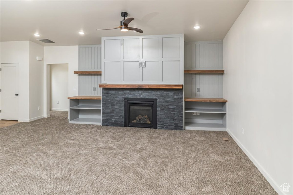 Unfurnished living room with a fireplace, light colored carpet, and ceiling fan