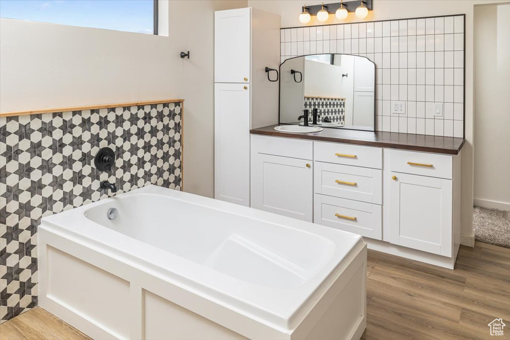 Bathroom featuring wood-type flooring, vanity, and a bathtub
