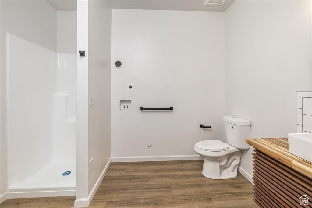 Bathroom featuring a shower, hardwood / wood-style flooring, and toilet