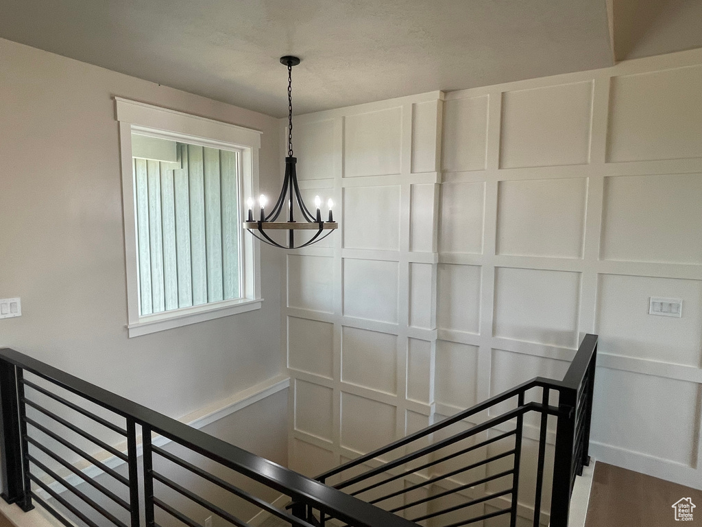 Stairway featuring hardwood / wood-style floors and an inviting chandelier