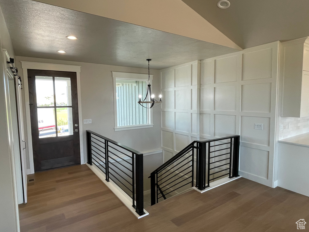 Foyer entrance featuring hardwood / wood-style flooring, an inviting chandelier, and lofted ceiling