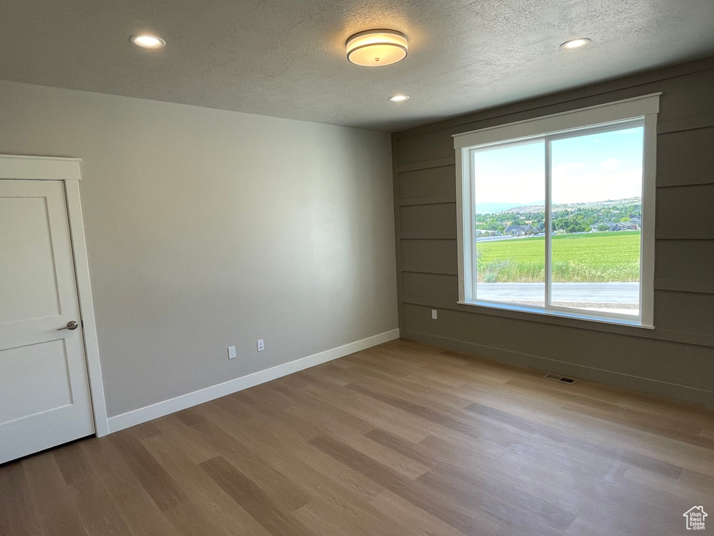 Unfurnished room with a textured ceiling and light wood-type flooring