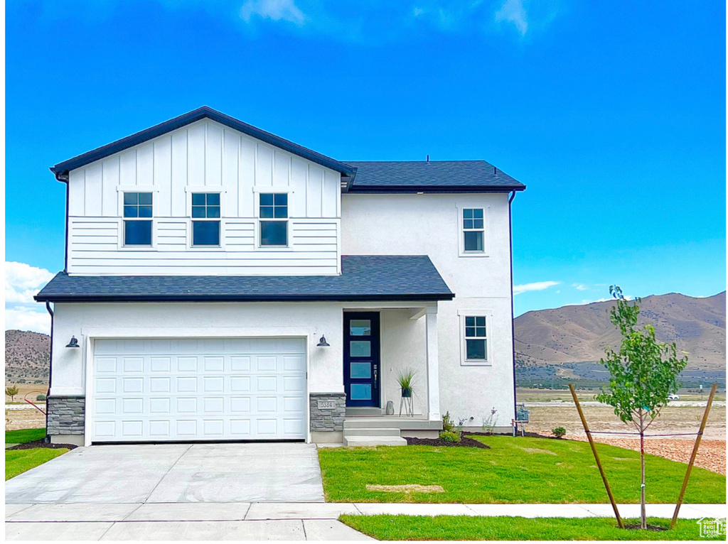 View of front facade featuring a mountain view, a garage, and a front yard