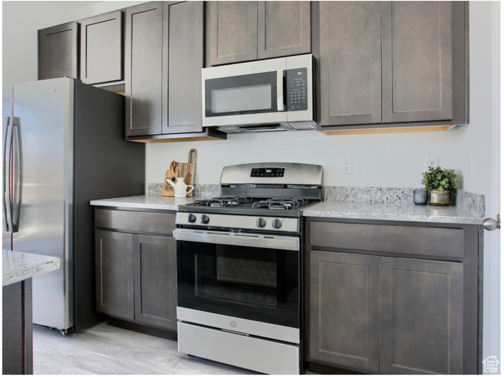 Kitchen featuring light stone countertops, appliances with stainless steel finishes, and light wood-type flooring