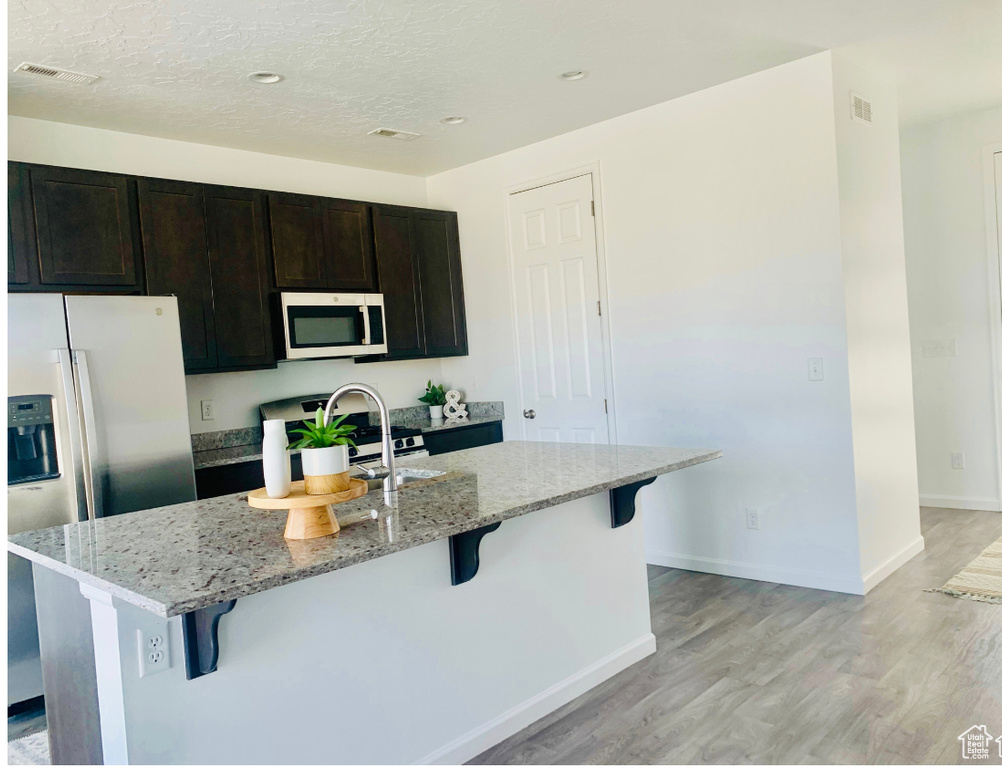 Kitchen featuring a kitchen breakfast bar, stainless steel fridge, and an island with sink