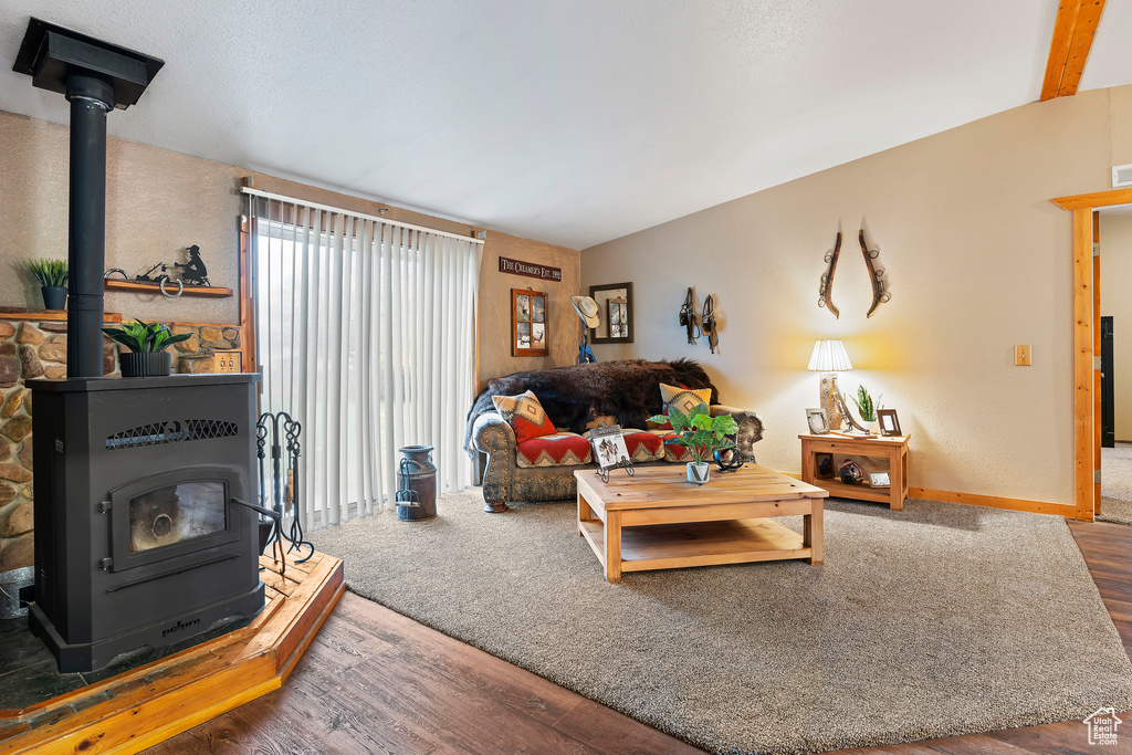 Living room with a wood stove, wood-type flooring, and lofted ceiling