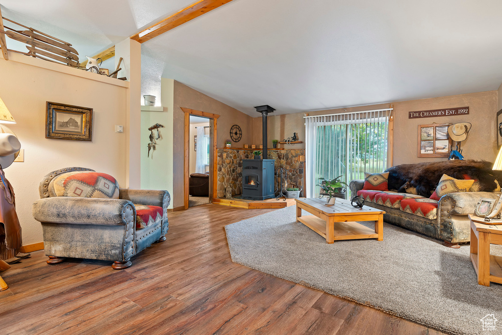 Living room featuring hardwood / wood-style floors, vaulted ceiling with beams, and a wood stove