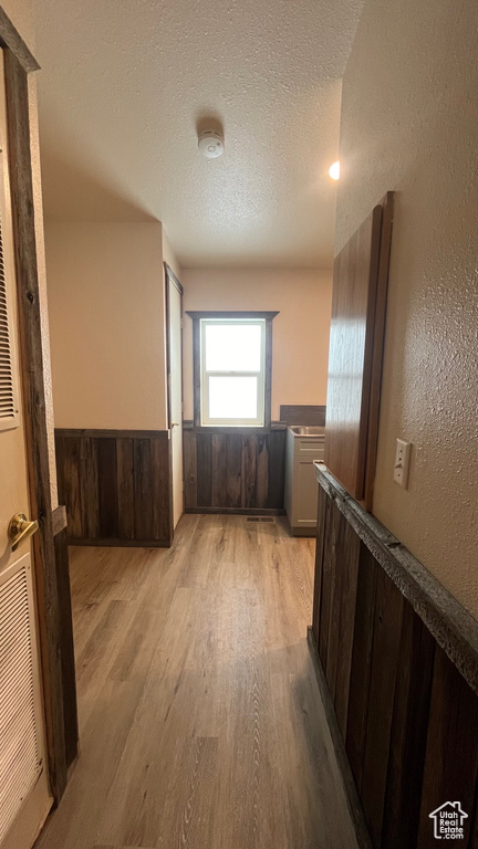 Corridor with light hardwood / wood-style floors and a textured ceiling