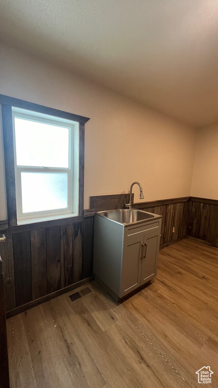 Kitchen featuring light hardwood / wood-style floors, sink, and wooden walls