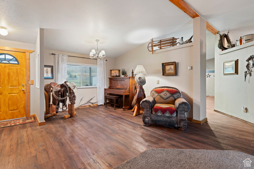 Entrance foyer with an inviting chandelier, dark hardwood / wood-style floors, and vaulted ceiling