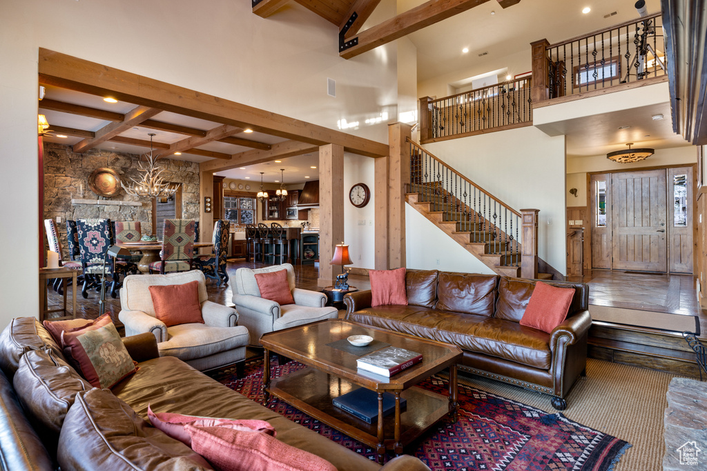 Living room with carpet, beam ceiling, a notable chandelier, and a high ceiling