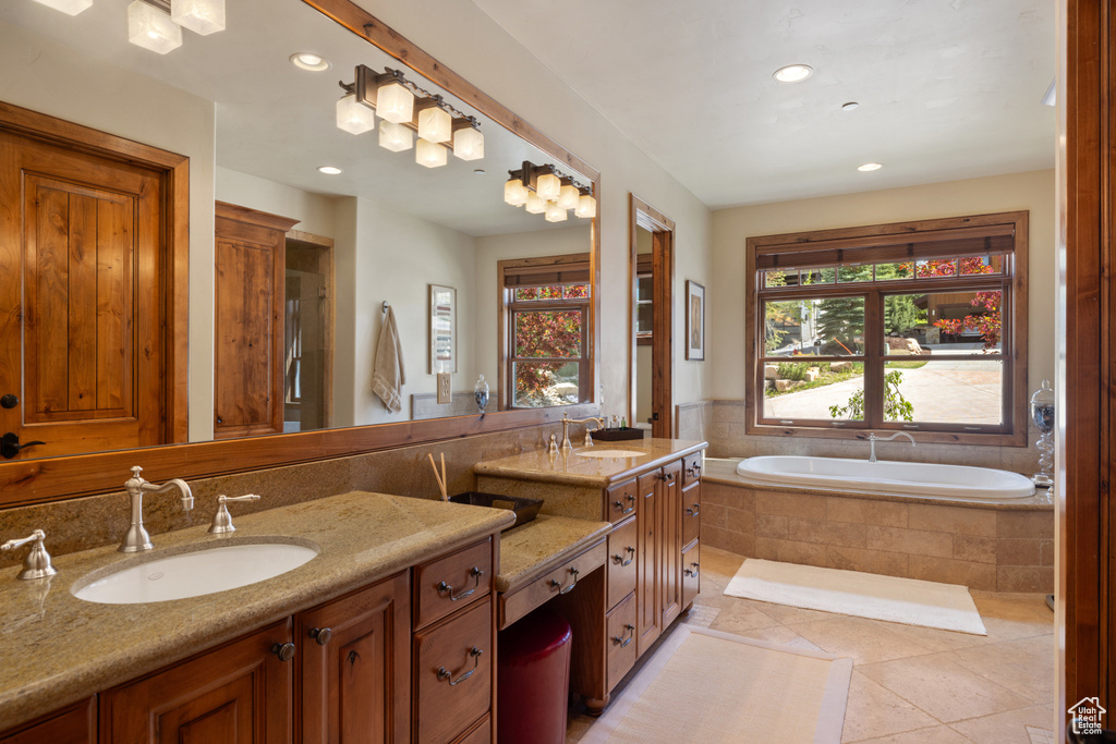 Bathroom with tile patterned floors, vanity, and tiled bath