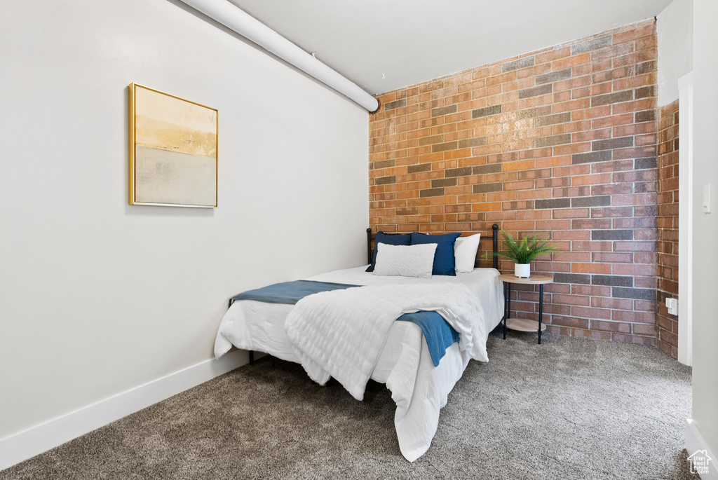 Bedroom with carpet and brick wall