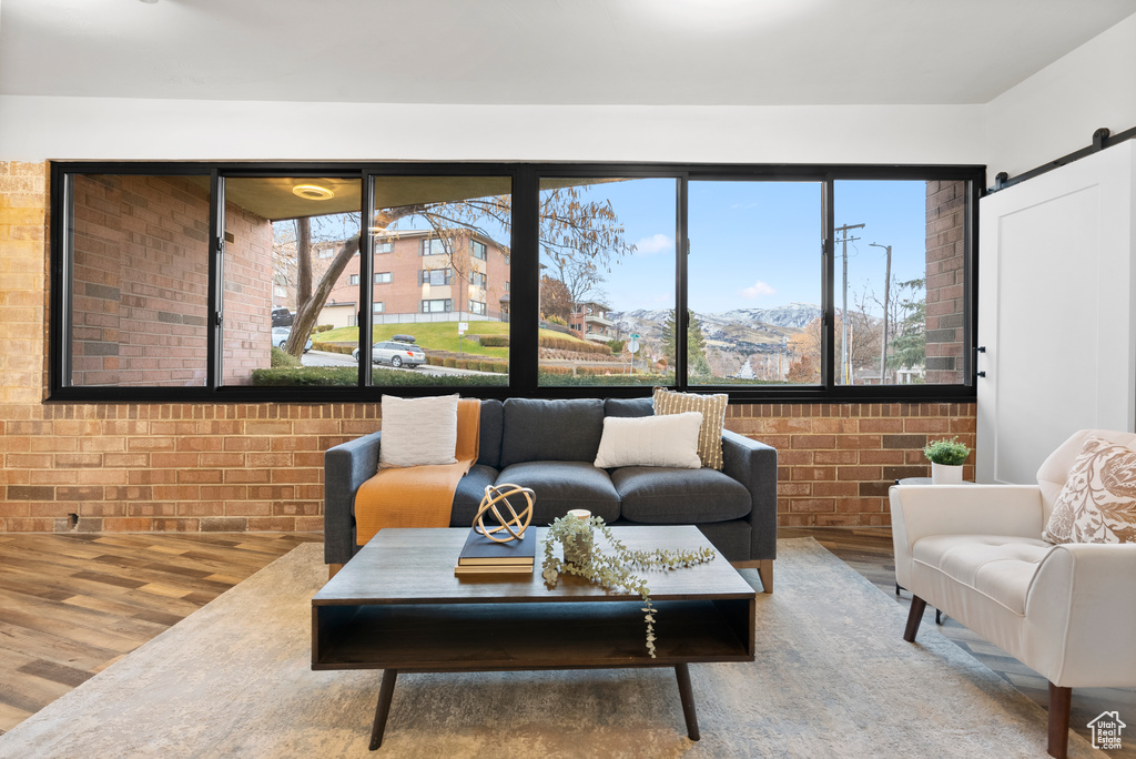 Living room featuring a barn door, brick wall, and wood-type flooring