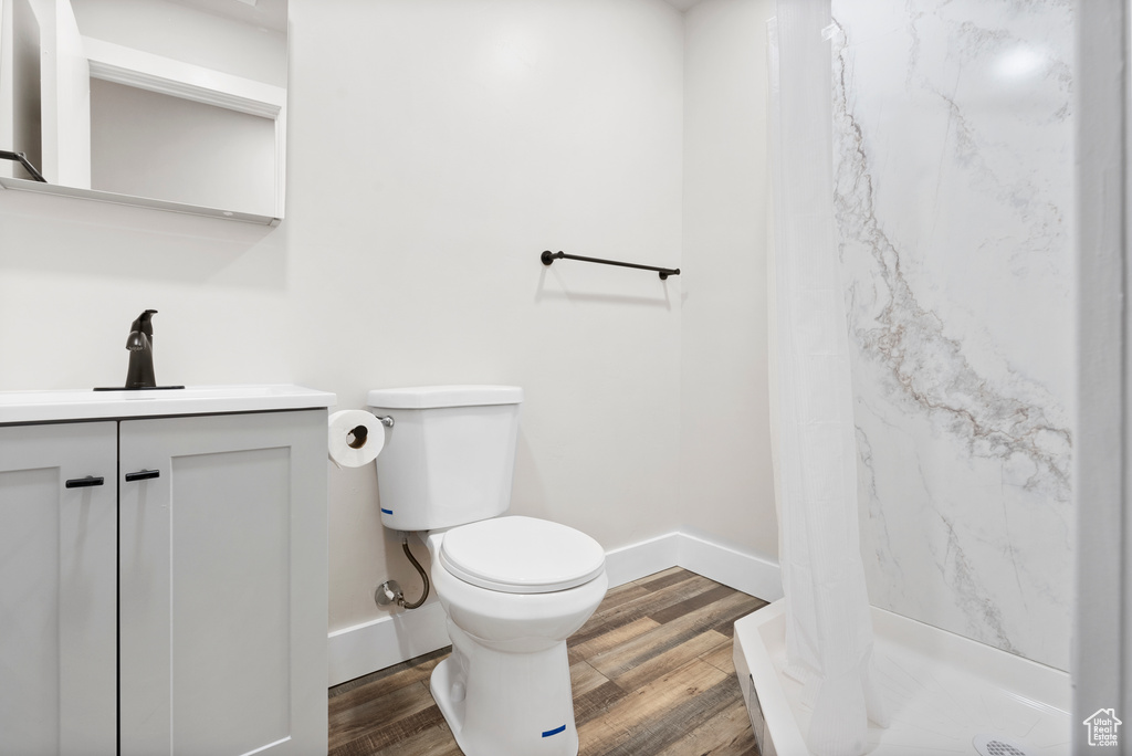 Bathroom with curtained shower, vanity, wood-type flooring, and toilet