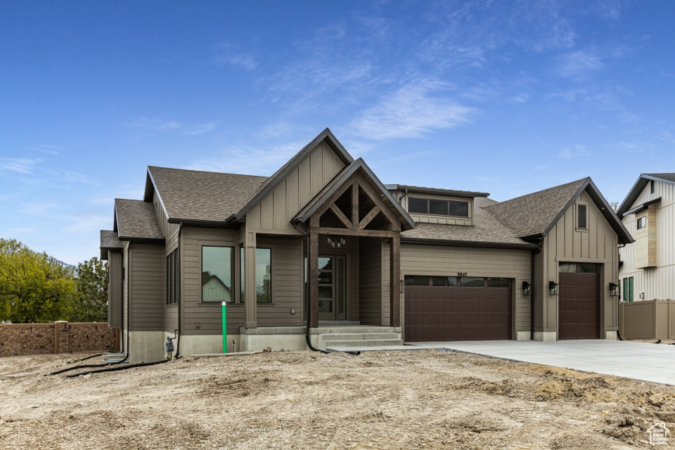 View of front of property featuring a garage, board and batten siding, driveway, and a shingled roof