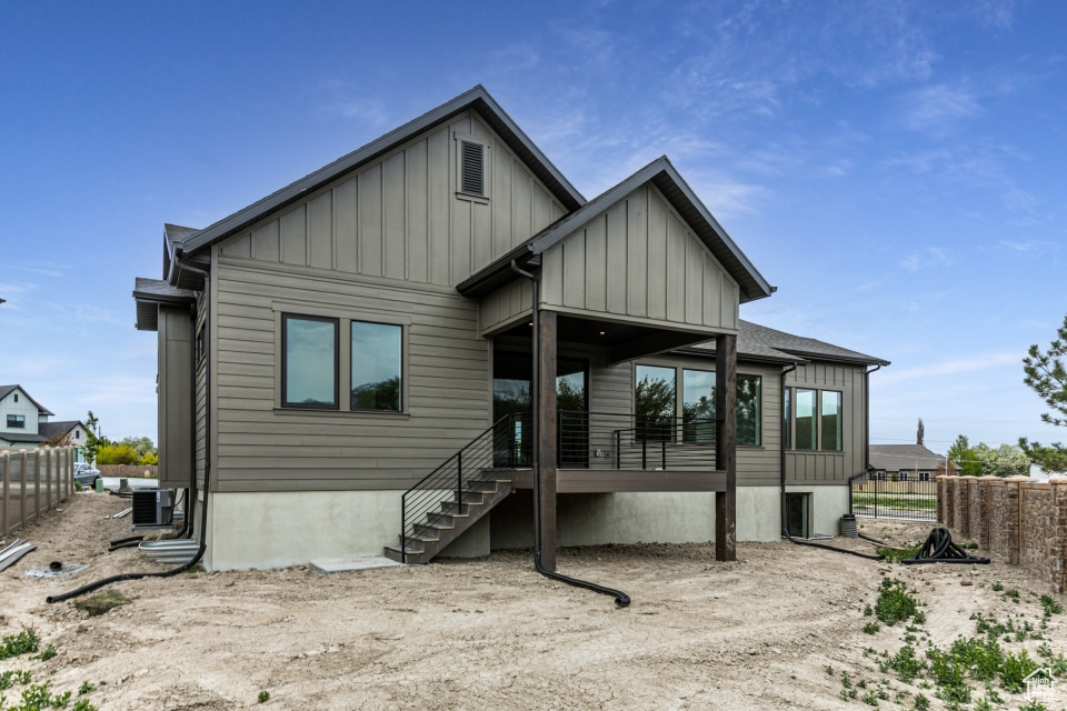 Rear view of property featuring fence, stairs, board and batten siding, and central air condition unit