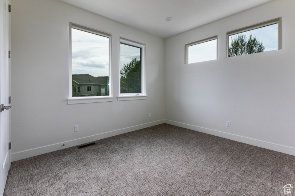 Carpeted spare room with baseboards and visible vents