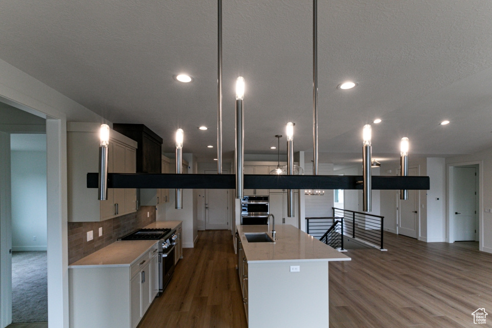Kitchen with a sink, light countertops, light wood-style flooring, stainless steel appliances, and baseboards