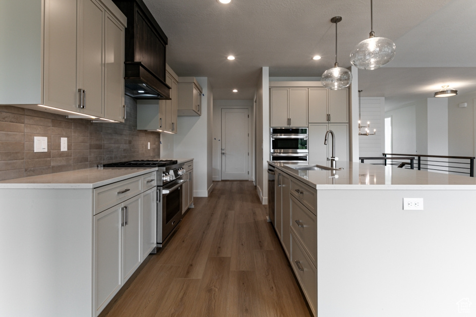 Kitchen with a sink, backsplash, stainless steel appliances, and light wood-style flooring