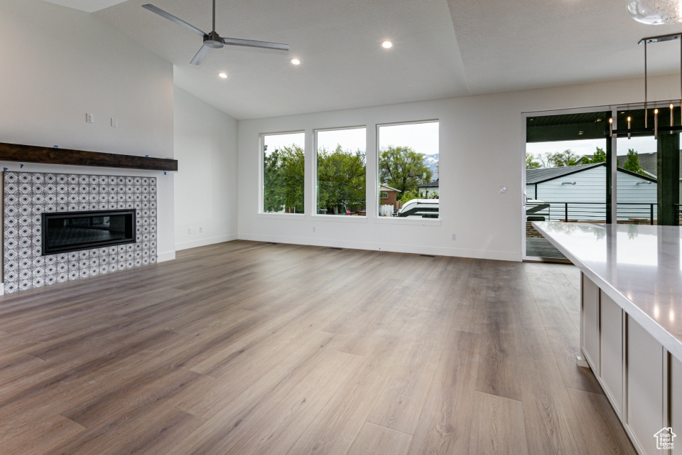 Unfurnished living room with a ceiling fan, baseboards, vaulted ceiling, and wood finished floors