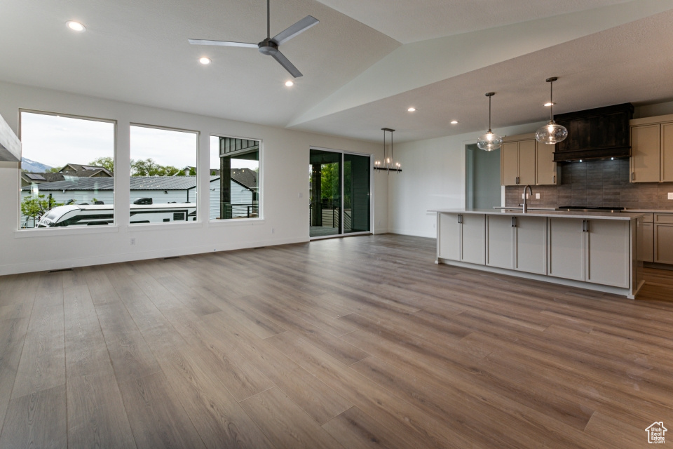 Unfurnished living room with wood finished floors, lofted ceiling, ceiling fan, recessed lighting, and a sink