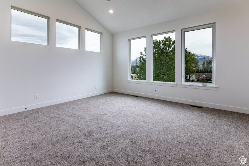 Carpeted spare room featuring baseboards, vaulted ceiling, recessed lighting, and visible vents