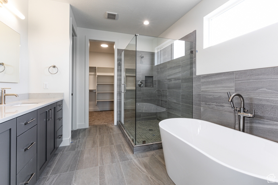 Bathroom featuring visible vents, vanity, recessed lighting, a soaking tub, and a shower stall