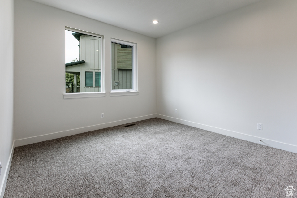 Carpeted spare room featuring baseboards, recessed lighting, and visible vents