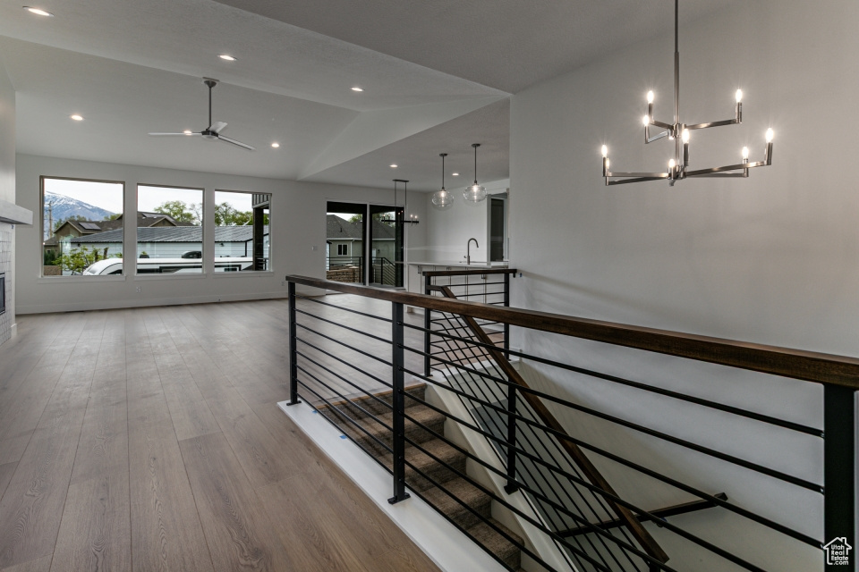 Hallway featuring vaulted ceiling, an upstairs landing, wood finished floors, a sink, and a chandelier