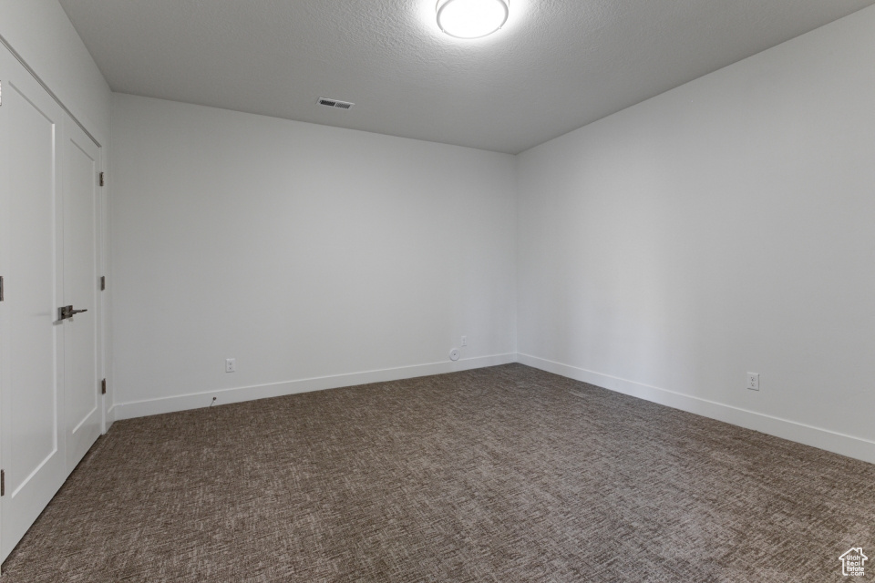 Carpeted empty room with visible vents and baseboards