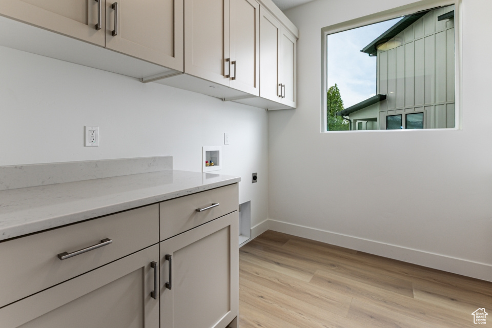 Clothes washing area with baseboards, hookup for a washing machine, light wood-type flooring, cabinet space, and hookup for an electric dryer
