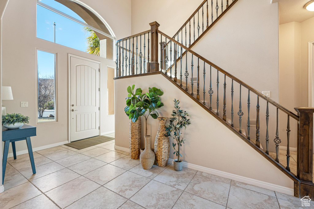 Foyer with a high ceiling, a healthy amount of sunlight, and light tile patterned flooring