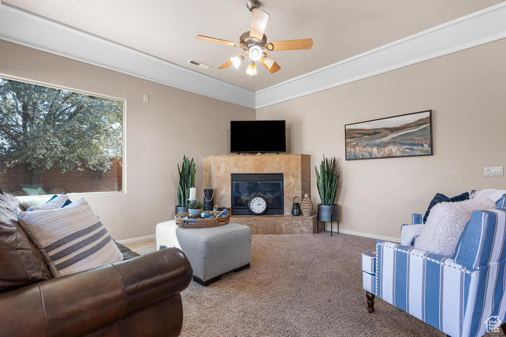 Carpeted living room featuring a tile fireplace and ceiling fan