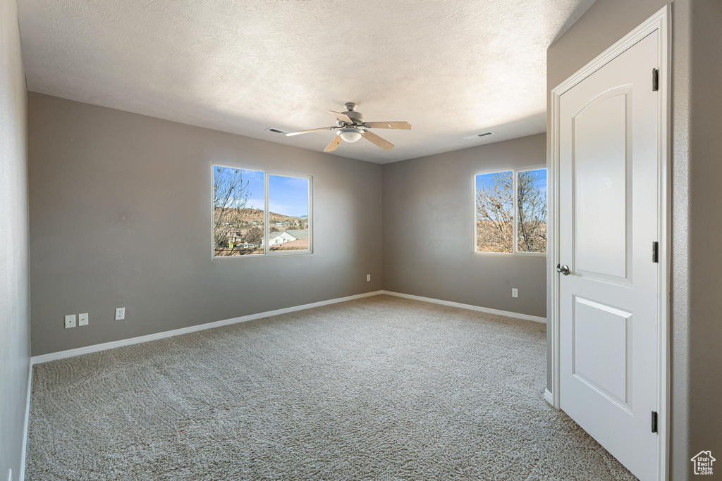 Unfurnished room with a textured ceiling, light colored carpet, and ceiling fan